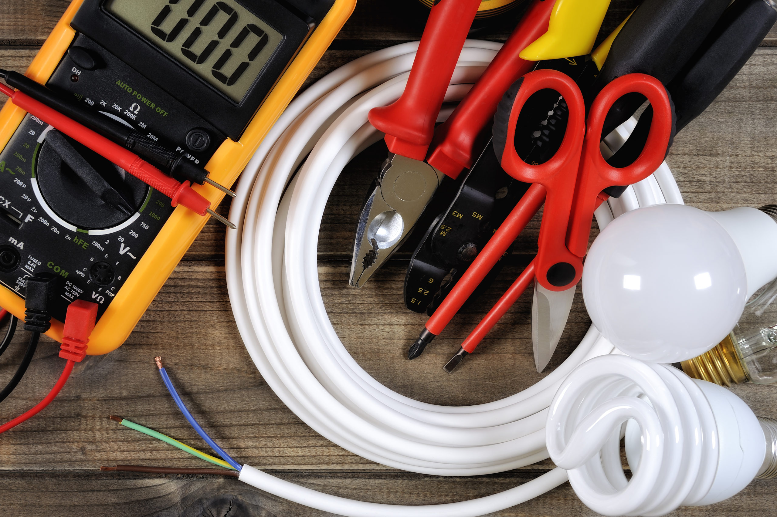 Top view of work tools and electrical system components on antique wooden background.